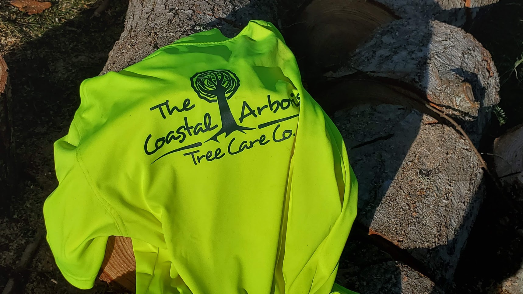 The Coastal Arborist t-shirt laying atop a wood pile in Campbell River